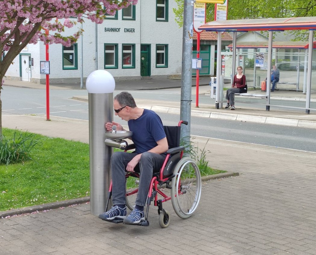 öffentliche Wasserspender, Trinkbrunnen im Aussenbereich an Bushaltestelle, mit Rollstuhl