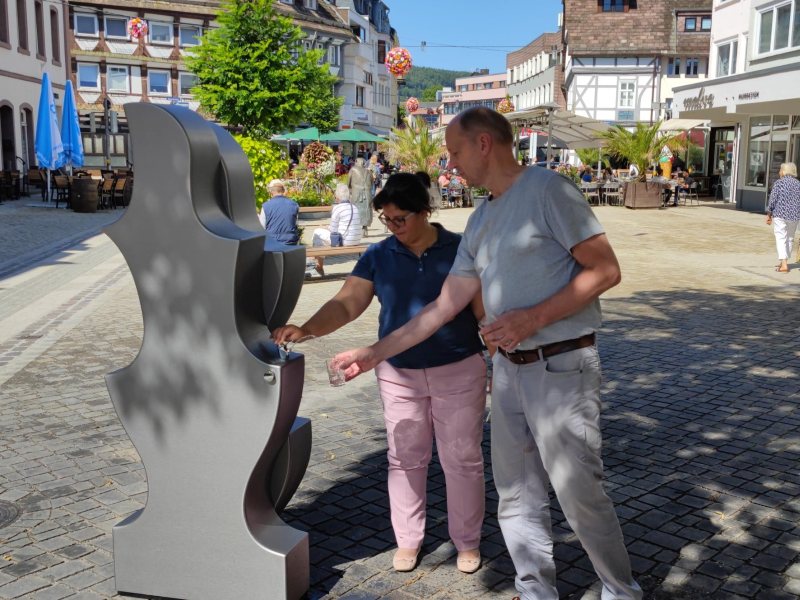 Öffentliche Wasserspender, Trinkbrunnen im Aussenbereich in Fußgängerzone mit Personen, die Trinkwasser zapfen