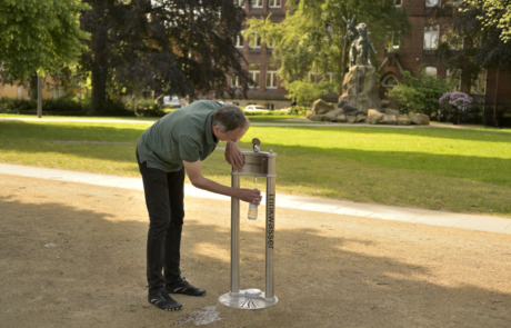 Himberg Trinkwasserbrunnen La Playa, Mann trinkt Himberg Trinkwasserbrunnen La Playa, Mann trinkt